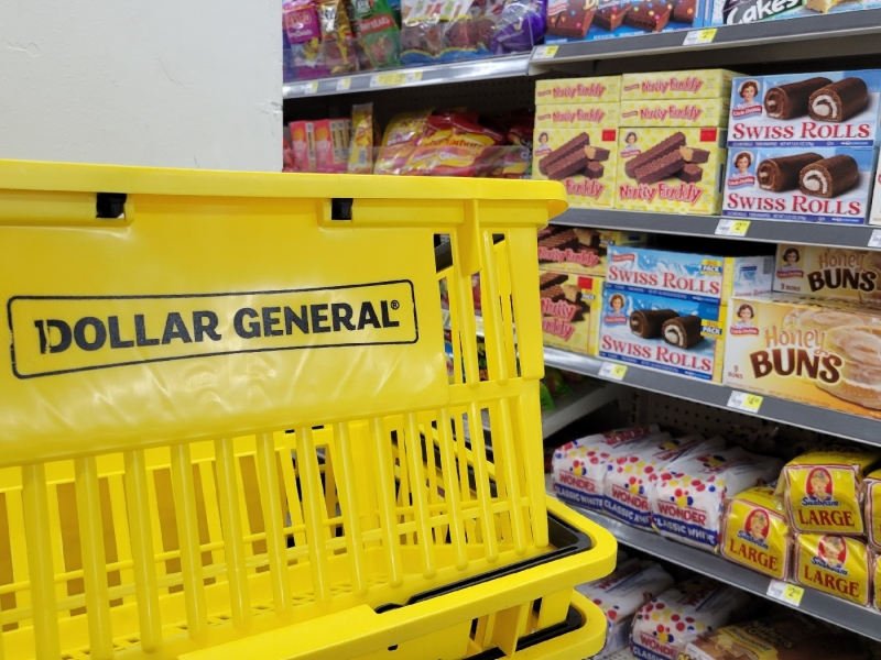 A Dollar General grocery basket placed near a store aisle with bread and pastries