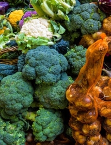 Seasonal produce at a market in October, including broccoli, eggplant, garlic, cauliflower