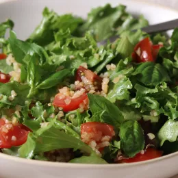 sliced tomato and cooked bulgur over leaf lettuce