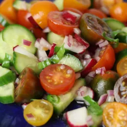 tomato, cucumber, radish salad on blue plate.