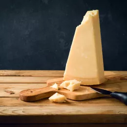 block of cheese on cutting board with knife