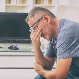 man sitting down and rubbing eyes