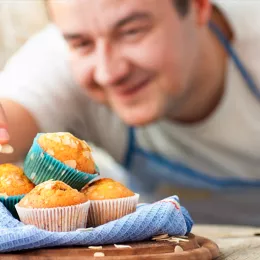 baker topping muffins with almonds