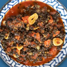 tomato and black lentil dish on blue and white plate