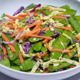 Plate with stir-fried snow peas, shredded carrots and cabbage