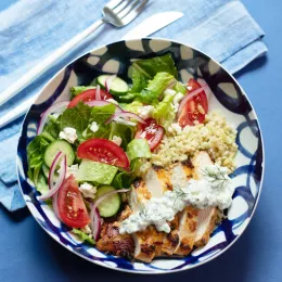 bowl on a blue background with greens and chicken