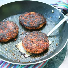 pan with three cooked chicken burger