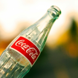 An empty bottle of Colca-Cola with a colorful blurred background