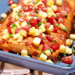 large piece of salmon covered in pineapple and tomato salsa on a pan