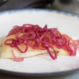 tilapia on a plate covered in cooked red onions