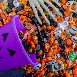 Halloween candy spilling out of purple pumpkin bucket