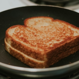 A well toasted grilled cheese sandwich in a frying pan. 