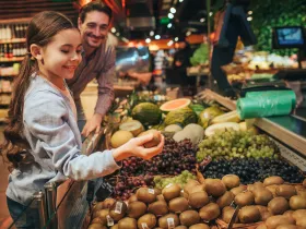 White daughter and father shopping for groceries in fruit section