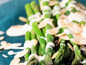 asparagus with almonds and sauce on plate