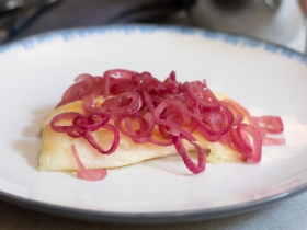 tilapia on a plate covered in cooked red onions