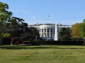 A picture of a large green lawn with the White House in the background