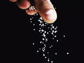 fingers sprinkling salt on a black background