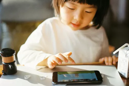 A young child watches cartoons on a small tablet