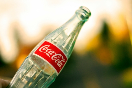 An empty bottle of Colca-Cola with a colorful blurred background