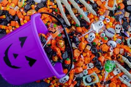 Halloween candy spilling out of purple pumpkin bucket