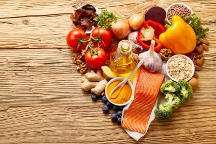 A collection of food in the shape of a heart including raw salmon, olive oil, ginger, nuts, berries, oats, beans, and assorted fruits and vegetables.