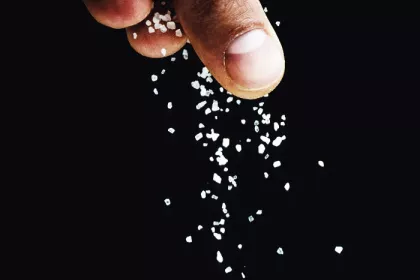 fingers sprinkling salt on a black background