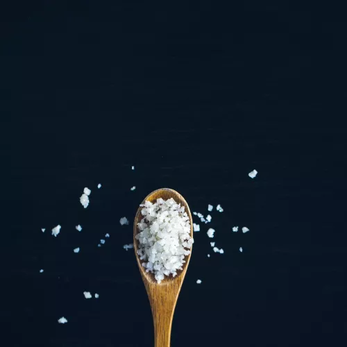 A wooden spoon overflowing with salt 