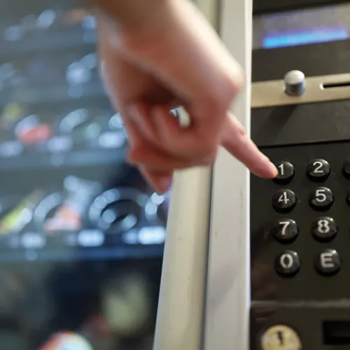 A hand making a choice at a vending machine