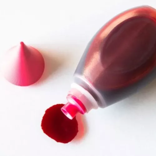 a bottle of red dye spilling onto a white surface