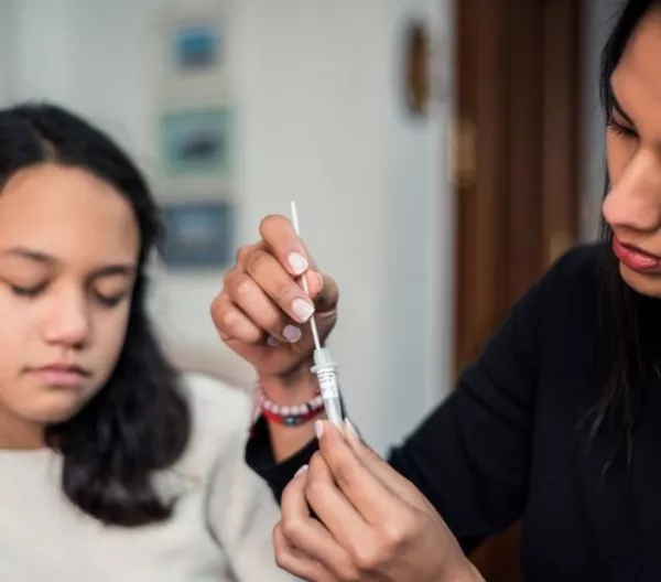 Mother following the instructions to collect a sample of the covid test result at home