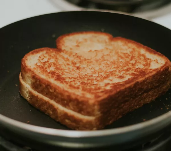 A well toasted grilled cheese sandwich in a frying pan. 