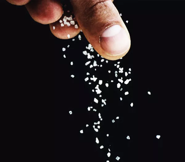 fingers sprinkling salt on a black background