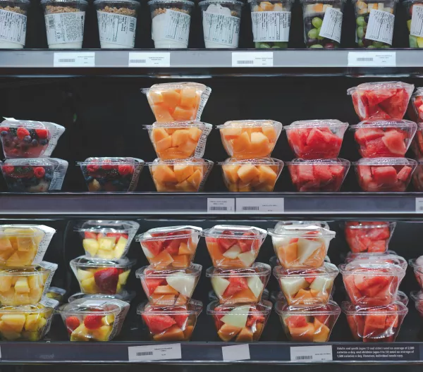 Supermarket shelves containing fruit salad and pre-cut fruits in plastic to go containers