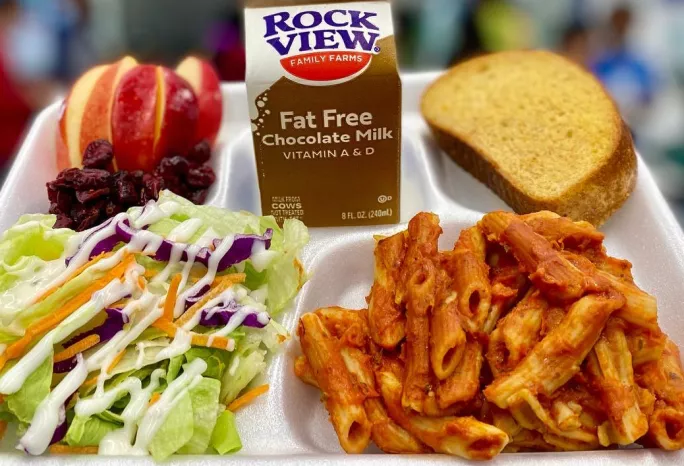 A lunch tray: penne with marinara, salad with ranch dressing, whole grain-rich bread, milk