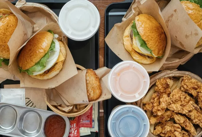 Flat lay of fast food burgers and fried foods with soda