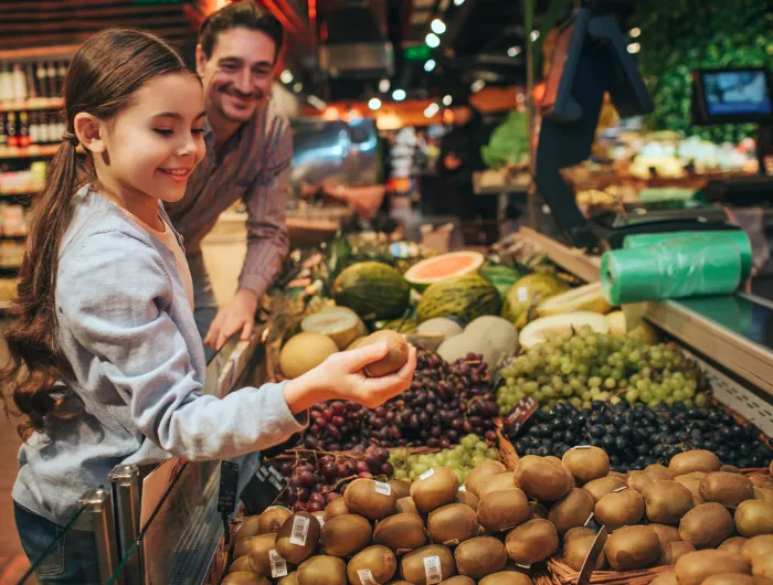 White daughter and father shopping for groceries in fruit section