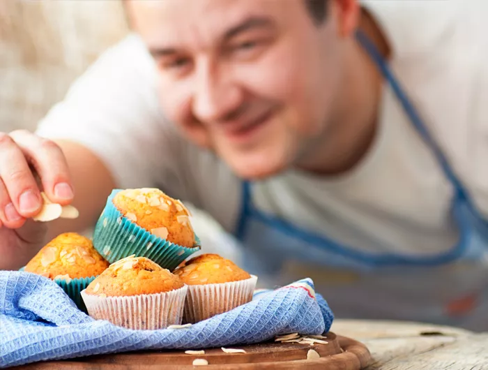 baker topping muffins with almonds