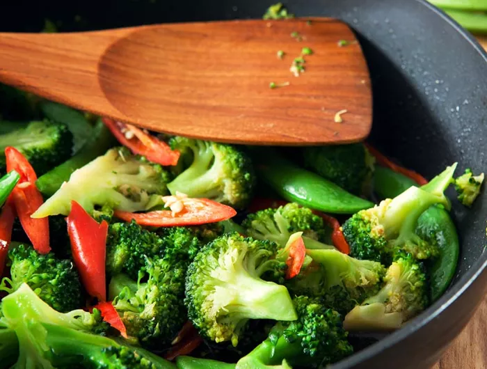 broccoli, peppers, snap peas in bowl with wooden spoon