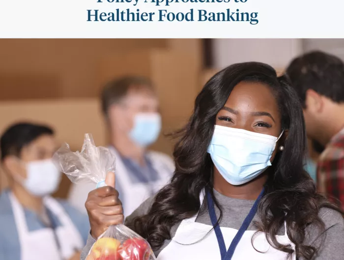 A woman of color holding a bag of apples at a food bank