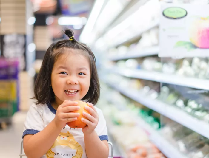 Girl holding an apple in grocery store