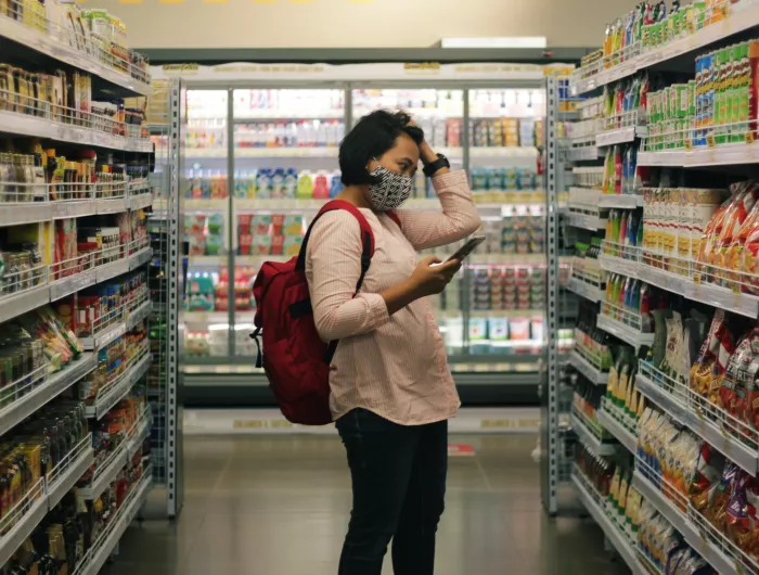 A woman in a grocery store peruses the snack aisle