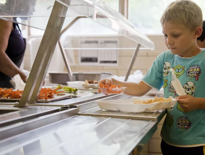 A young boy takes food for his lunch tray from a buffet