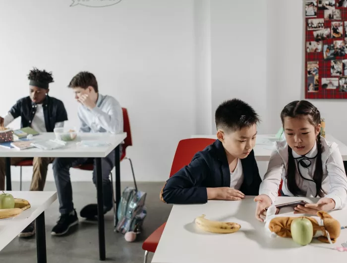 Two pairs of students eat at lunch tables