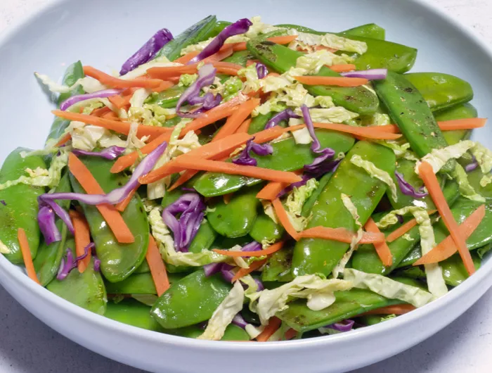 Plate with stir-fried snow peas, shredded carrots and cabbage