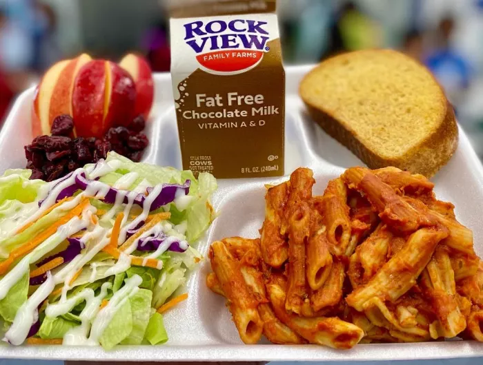 A lunch tray: penne with marinara, salad with ranch dressing, whole grain-rich bread, milk