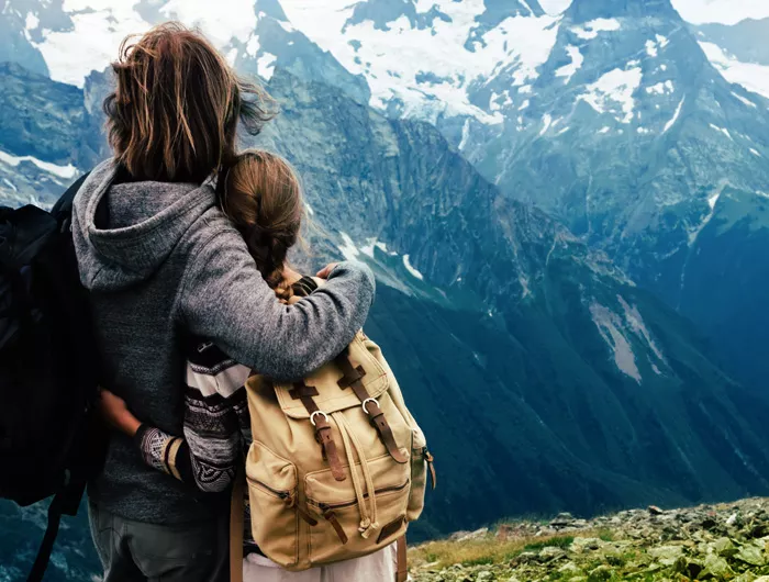 woman and young girl standing together looking over snow capped mountains