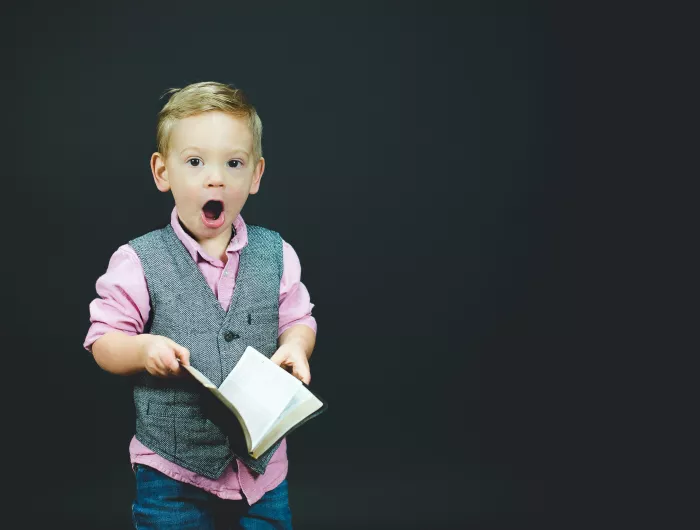 A young boy surprised by the contents of a book he's reading