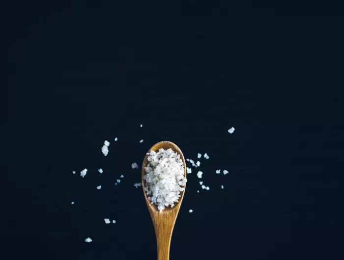 A wooden spoon overflowing with salt 