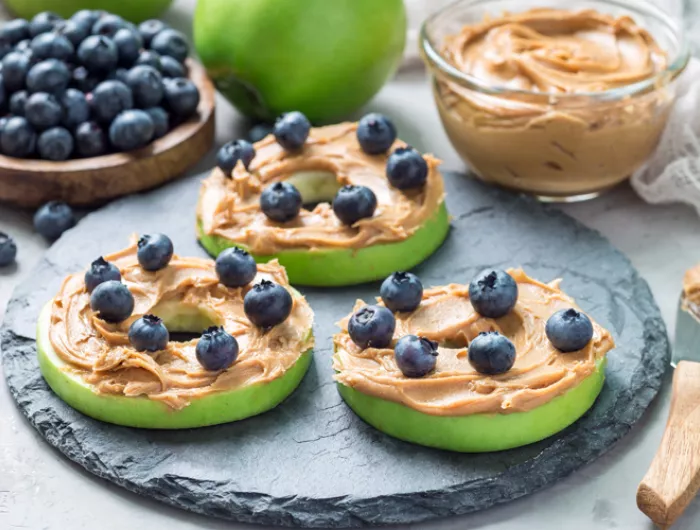 Plate with green apple slices covered in peanut butter and sprinkled with blueberries