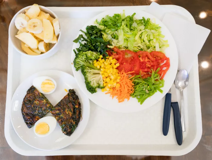 Vegetable salad, spinach omelette and fruit on tray